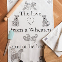Load image into Gallery viewer, The Love From A wheaten Cannot Be Beaten Teatowel. White cotton tea towel with paws, heart and dogs on
