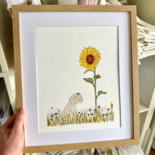 Load image into Gallery viewer,  light oak wood framed art print featuring a yellow sunflower and a dog in a grassy field.
