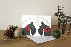 scottish terriers under mistletoe wearing red ribbons