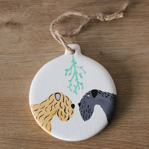 Kerry blue Terrier and Soft Coated wheaten Terrier Christmas Decoration by Harriet Billingham Illustration. Two terriers under mistletoe on a round ceramic ornament