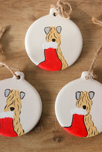 Load image into Gallery viewer, ceraminic christmas decoration hand painted with a soft coated wheaten terrier on it holding a stocking from its mouth
