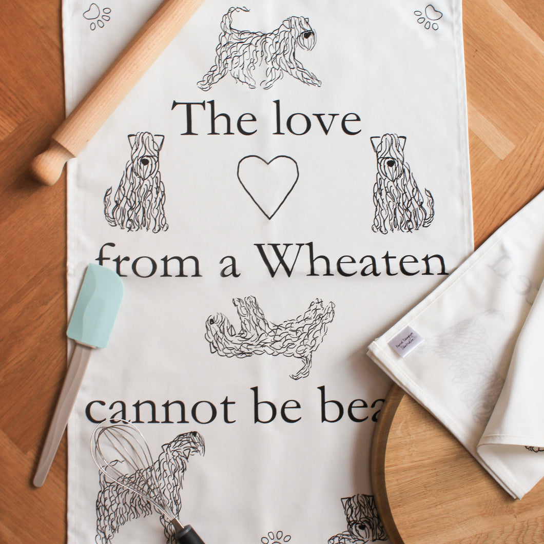 The Love From A wheaten Cannot Be Beaten Teatowel. White cotton tea towel with paws, heart and dogs on
