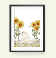 A framed art print featuring a whimsical illustration of a soft coated wheaten terrier among yellow sunflowers and green grass, displayed on a light beige wall.